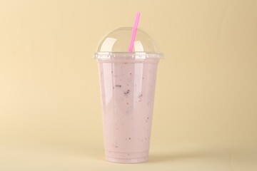 Plastic cup of tasty smoothie on beige background
