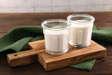 Glasses of tasty milk on wooden table, space for text