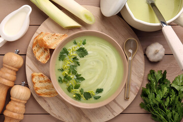 Delicious leek soup served on beige wooden table, flat lay
