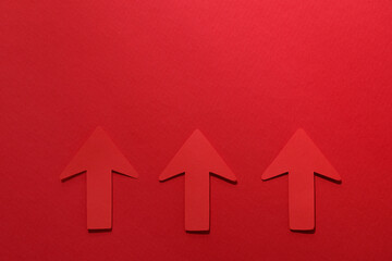 Paper arrows on red background, flat lay. Space for text