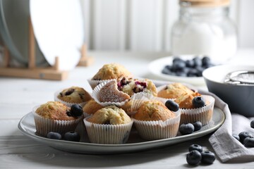 Delicious sweet muffins with blueberries on white wooden table