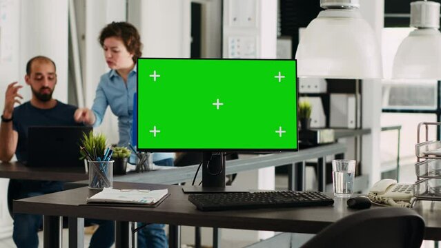 Greenscreen template on pc in office, modern computer showing isolated chromakey display in coworking space with employed agency people. Blank mockup screen on monitor, empty desk.
