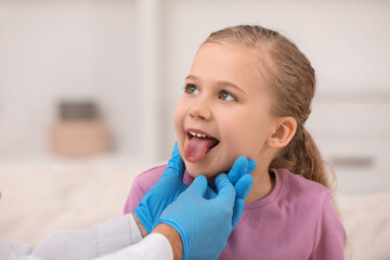 Doctor examining girl`s oral cavity indoors, closeup