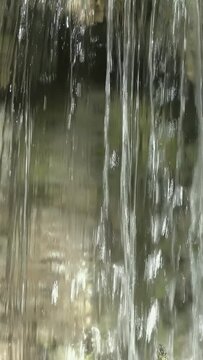 Beautifully flowing streams of a waterfall closeup. Vertical video
