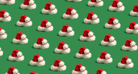 Many Santa hats on green background. Pattern for design