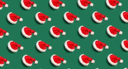 Many Santa hats on green background. Pattern for design