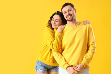 Happy young couple hugging on yellow background