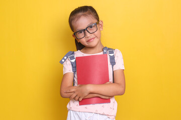 Portraif of smart little Asian girl wear glasses and backpack, holding books and looking at camera confidently