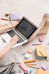 Fototapeta na wymiar Woman with laptop, makeup products and accessories shopping online on beige carpet, closeup