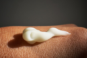 A smear of white moisturizer or sunscreen on a woman's hand.