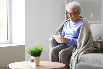 Senior woman writing in notebook at home