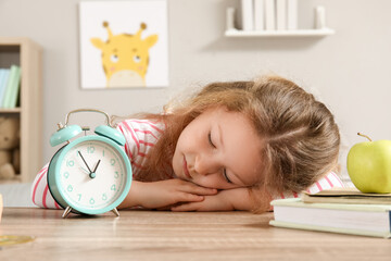 Cute little girl with alarm clock sleeping at home