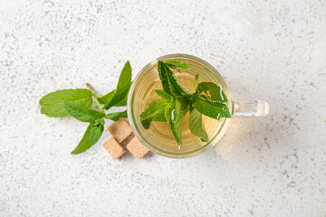 Cup of fresh mint tea with cane sugar on grunge light background
