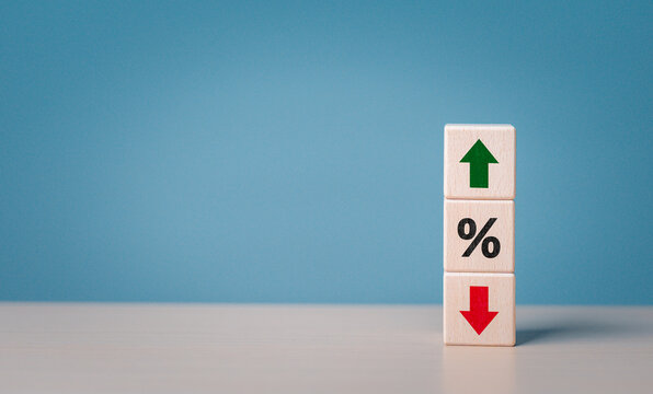 Staked wooden cube blocks with percentage symbol, green arrow up, and red arrow down icons. Interest rate financial and mortgage rates concept. Loan mortgage, VAT, tax, sale price. Stock investment.