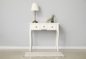 Dressing table with lamp near white wall