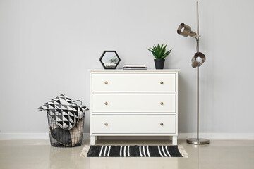 Standard lamp and chest of drawers near white wall