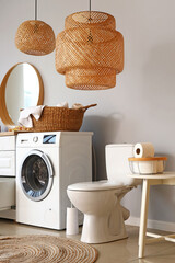 Interior of light restroom with ceramic toilet bowl and washing machine