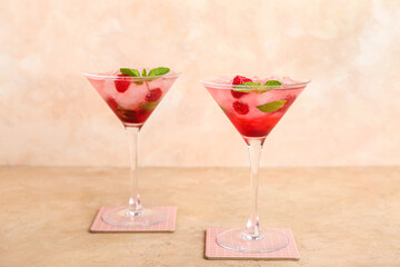 Glasses of fresh raspberry mojito on beige background