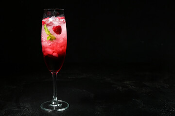 Glass of fresh raspberry mojito on black background