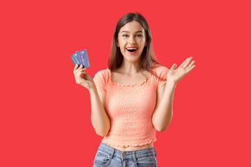 Happy young woman with credit cards on red background