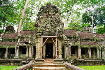Ta Phrom - Iconic 12th century Angkor Khmer Temple with Tree roots intertwined with the temple...