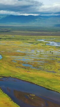 Aerial view of Avacha river delta and hilly landscape, Kamchatka Peninsula, Russia. Vertical video