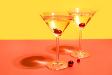Glasses of cocktail with Christmas balls on color background