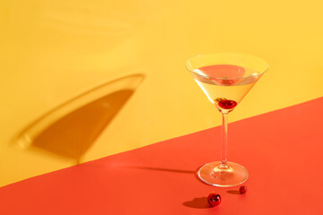 Glass of cocktail with Christmas balls on color background