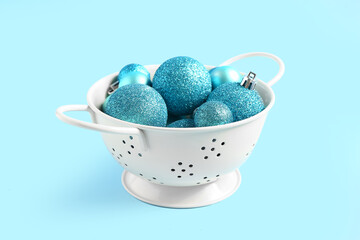Colander with beautiful Christmas balls on color background