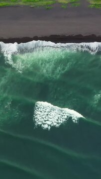 Aerial top view of Khalaktyrsky beach with black sand on Kamchatka peninsula, Russia, Pacific ocean. Vertical video