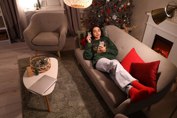 Young woman with mobile phone and credit card shopping online for Christmas at home