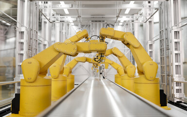 Front view, Yellow robot arms in a production line over a conveyor belt in a modern factory.