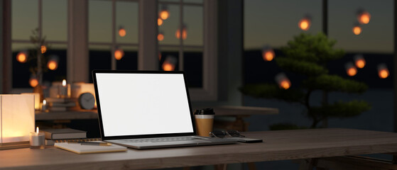 A white-screen laptop mockup on an office desk in a modern dark office room at night. close-up image