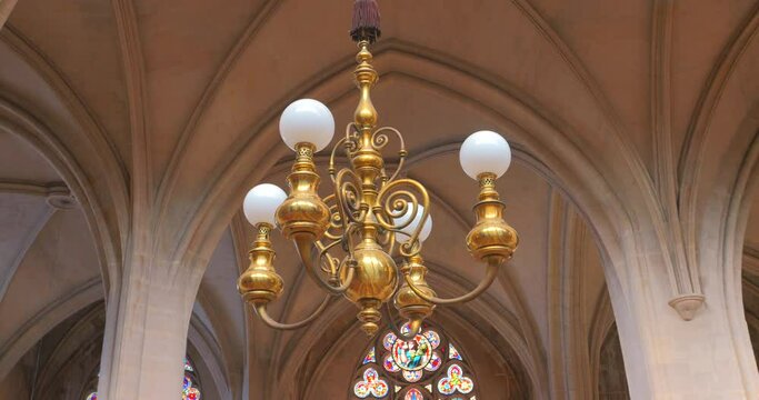 Low angle shot of a chandelier hanging from ceiling inside roman catholic church Saint-Germain-l'Auxerrois in Paris, France.