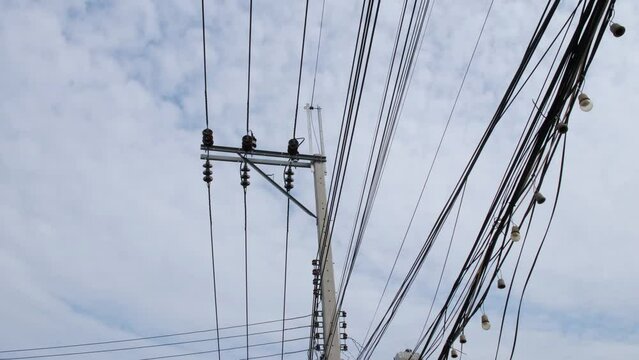 Entagled overhead electrical cables and wires in the middle of the city of Bangkok, in Thailand.