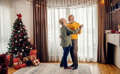 A happy senior couple is dancing at home on christmas and new year.