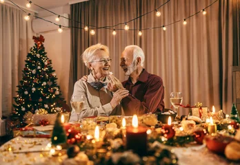 Foto op Aluminium A senior man is feeding his wife with cookie at christmas table on christmas and new year's eve at home. © dusanpetkovic1
