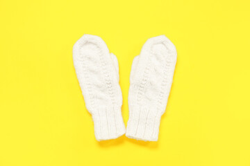 Pair of stylish knitted mittens on yellow background