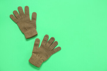 Pair of stylish warm gloves on green background