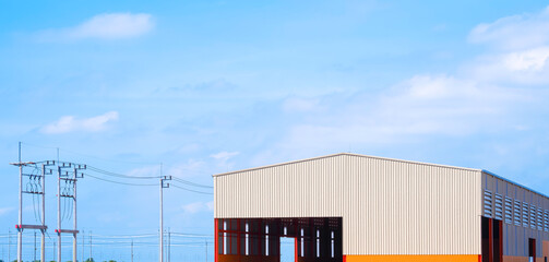 Industrial workshop building with electric poles and cable lines against blue sky background in panoramic view - obrazy, fototapety, plakaty