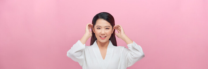 adorable smiling asian woman tuck hair behind ears on pink banner