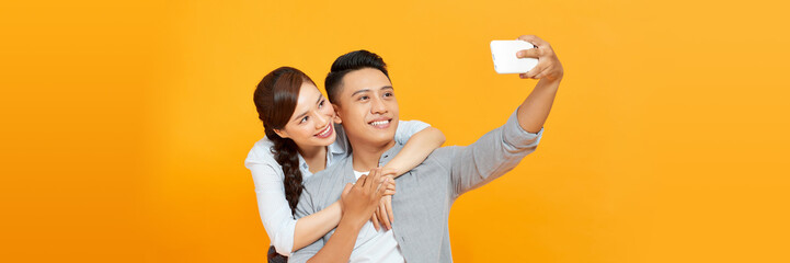 Young lovely couple taking selfie against yellow background