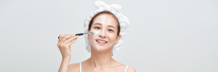 happy woman with a towel on her head apply a cleansing mask on her face. Banner