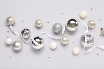 Silver Christmas balls with ribbon and confetti on white background