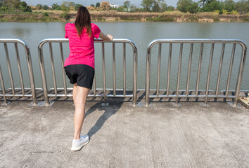 Obraz premium Rear view of runner woman doing stretching and warming up her legs before running. The benifit of stretching can increasing flexibility performance and reduce risk of injury.