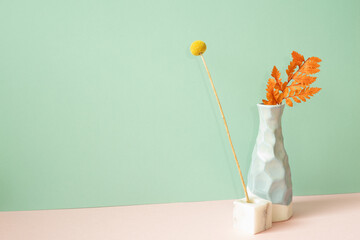 Vase of yellow and orange dry flower on pink table. mint green wall background. minimal interior