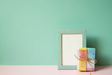Picture frame and gift box on pink table. mint green wall background. copy space