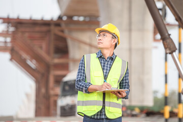 Engineer man with clipboard checklist in construction site, Industrial worker at infrastructure site, Foreman in hardhat in industry containers cargo