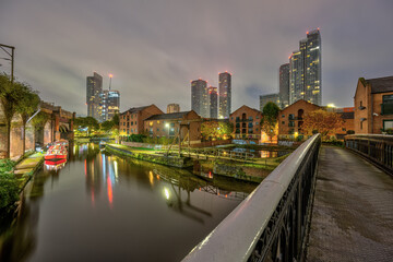 Castlefield in Manchester, UK, at night with the modern skyline in the back