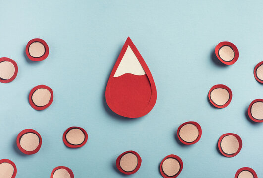 Drop of blood and red blood cells on pastel blue background. Iron deficiency anemia concept, low red blood cell. Top view